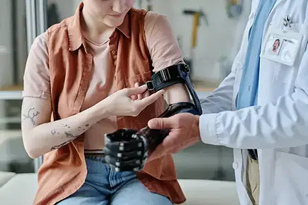 doctor fitting young woman with prosthetic arm